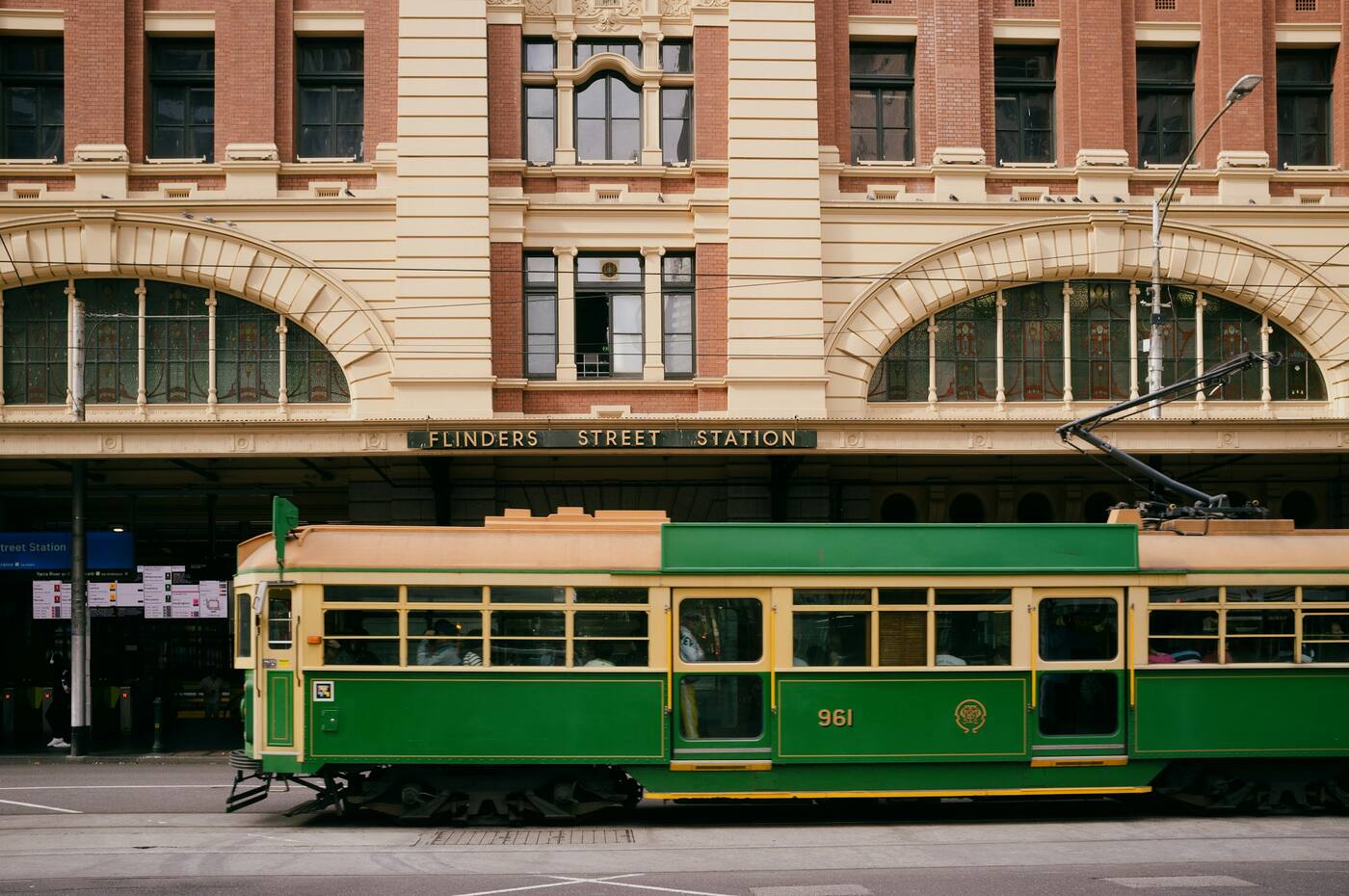 A green and gold W-class tram passing Flinders Street Station